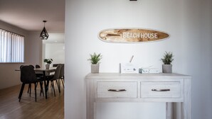 Una cocina moderna con encimera blanca, dos cajones y un letrero de madera que dice 'BEACH HOUSE'.
