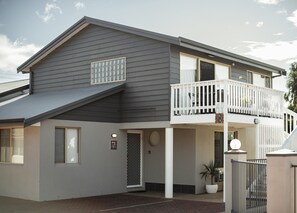 A two-story house with a balcony, a garage, and a driveway. - Archipelago Apartments (Castletown)