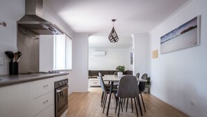 Una cocina moderna con horno empotrado, campana extractora de acero inoxidable y un comedor con mesa y sillas.