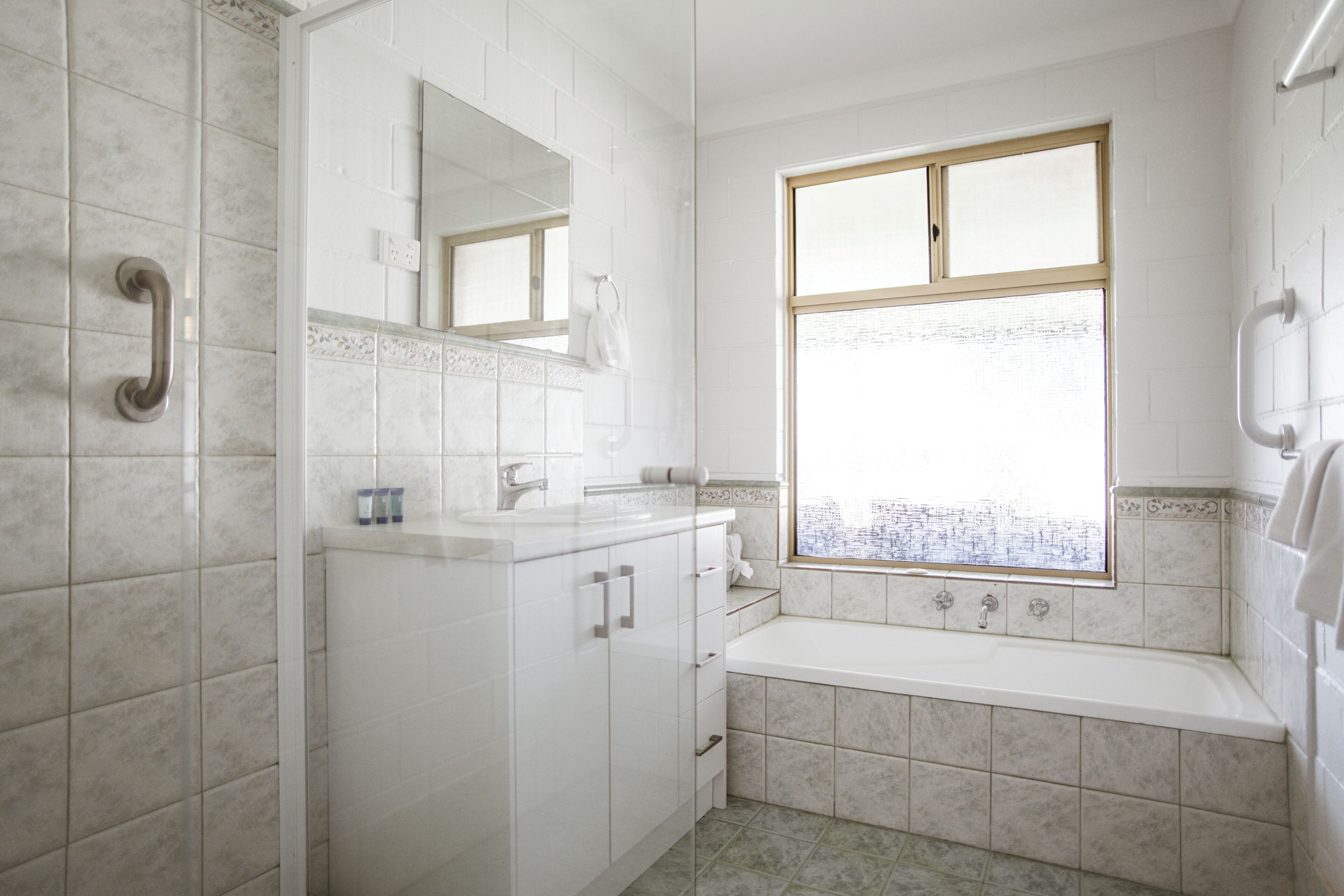 A bathroom with a bathtub, a sink, and a window with a view.