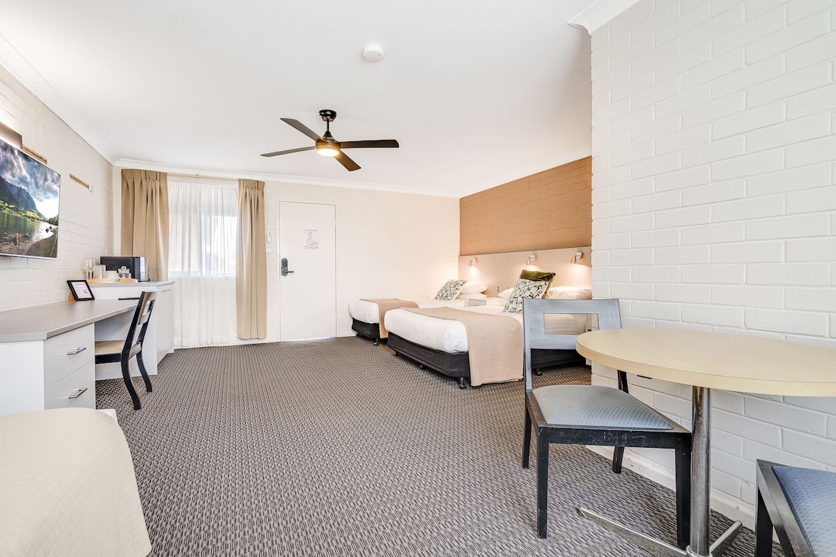 Una habitación de hotel con cama, escritorio, silla y una mesa redonda.