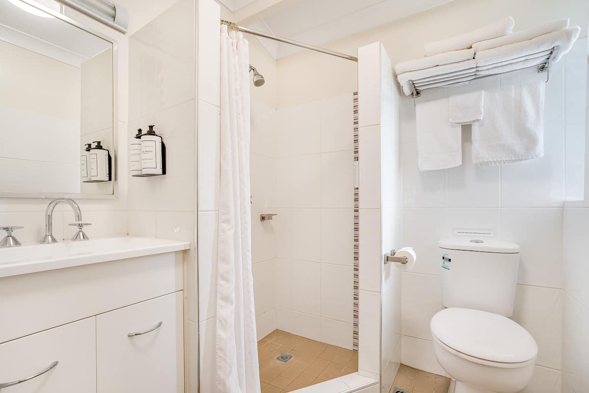 Un baño moderno con ducha, inodoro, lavabo y espejo.