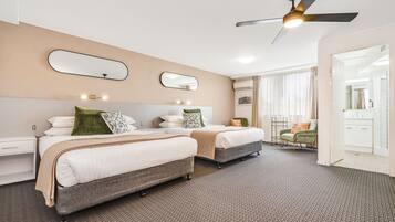 A hotel room with two beds, a ceiling fan, and a bathroom visible through an open door.