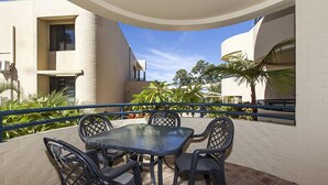 Un patio techado al aire libre con una mesa y sillas, rodeado por un muro blanco y una barandilla azul.