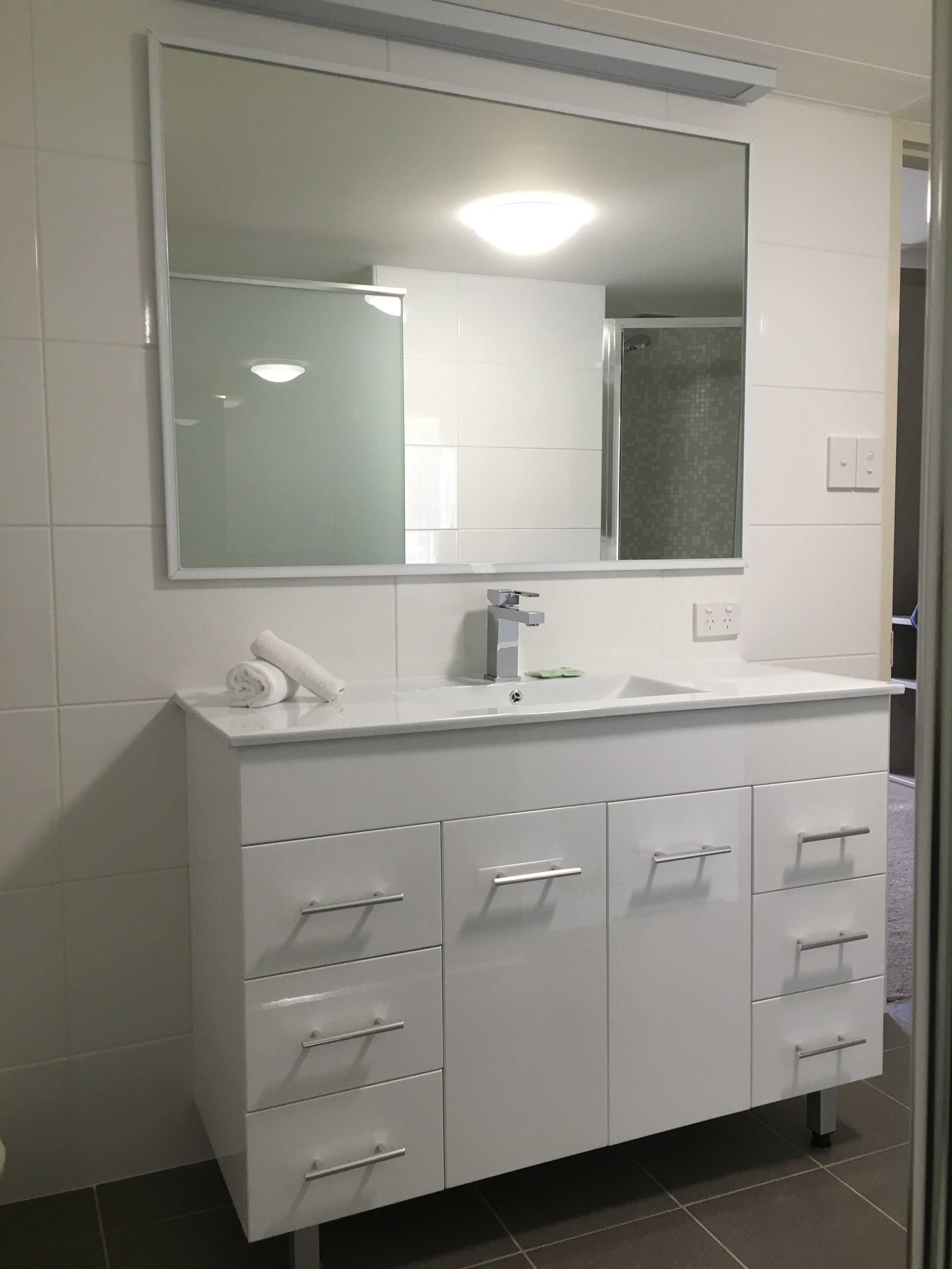 Un baño con un tocador blanco, un espejo grande y una zona de ducha.