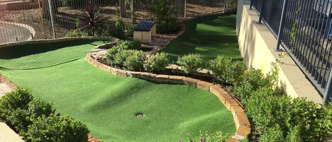 A well-maintained garden with a curved lawn, a small pond, and a variety of flowering plants.