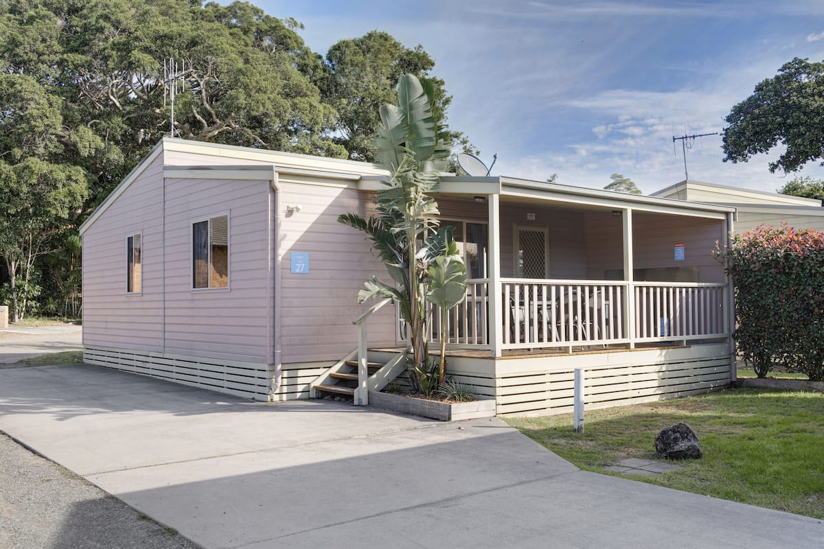Ein Bungalow mit Veranda, kleinem Vorgarten und Satellitenschüssel.