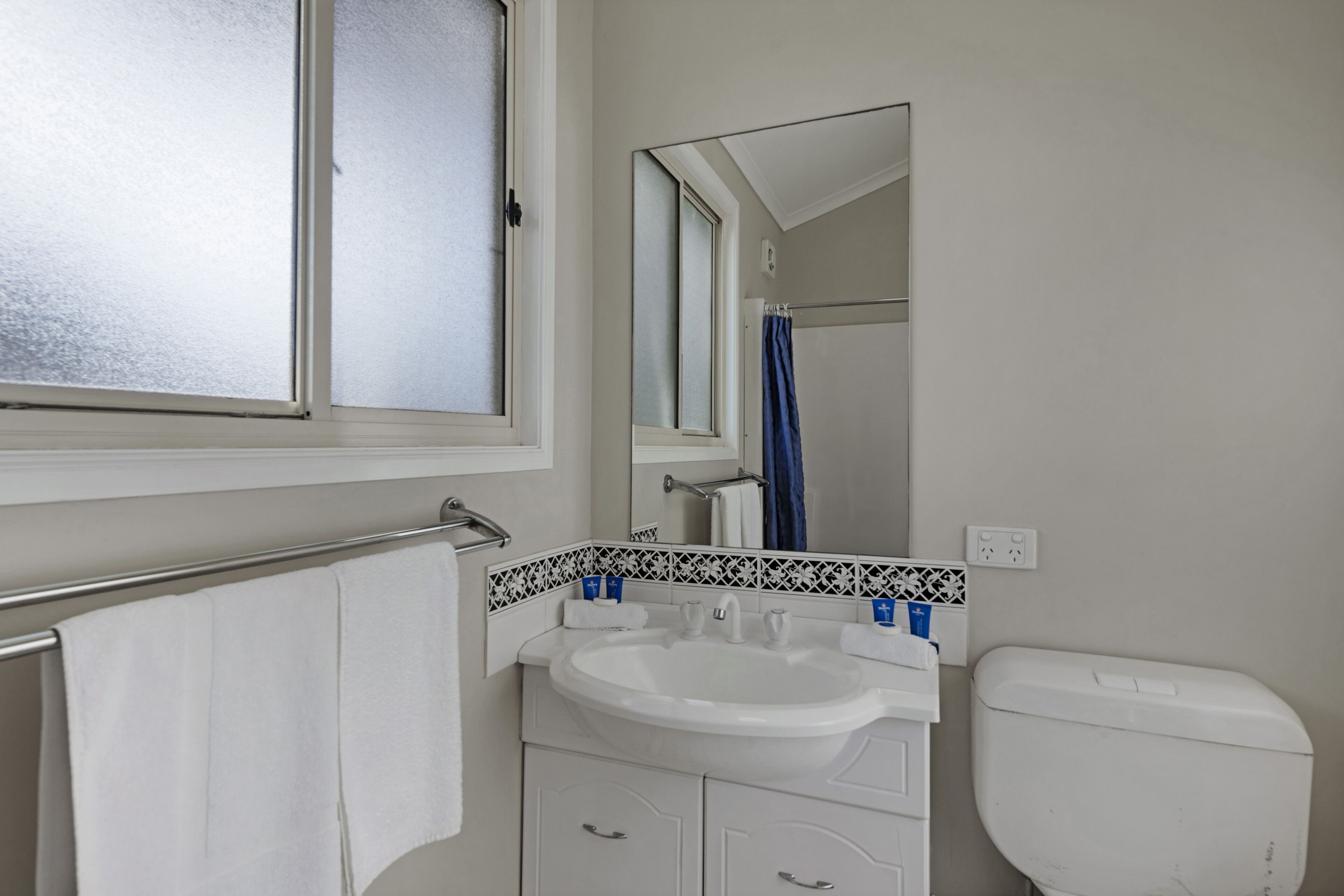 A bathroom with a white sink, a mirror, a towel rack, and a toilet.