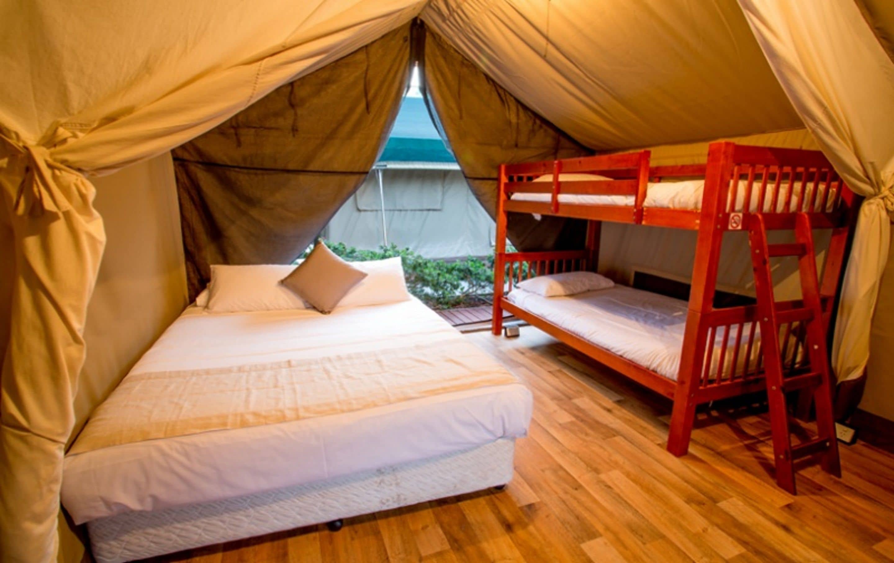 A tented accommodation with a single bed and a bunk bed.