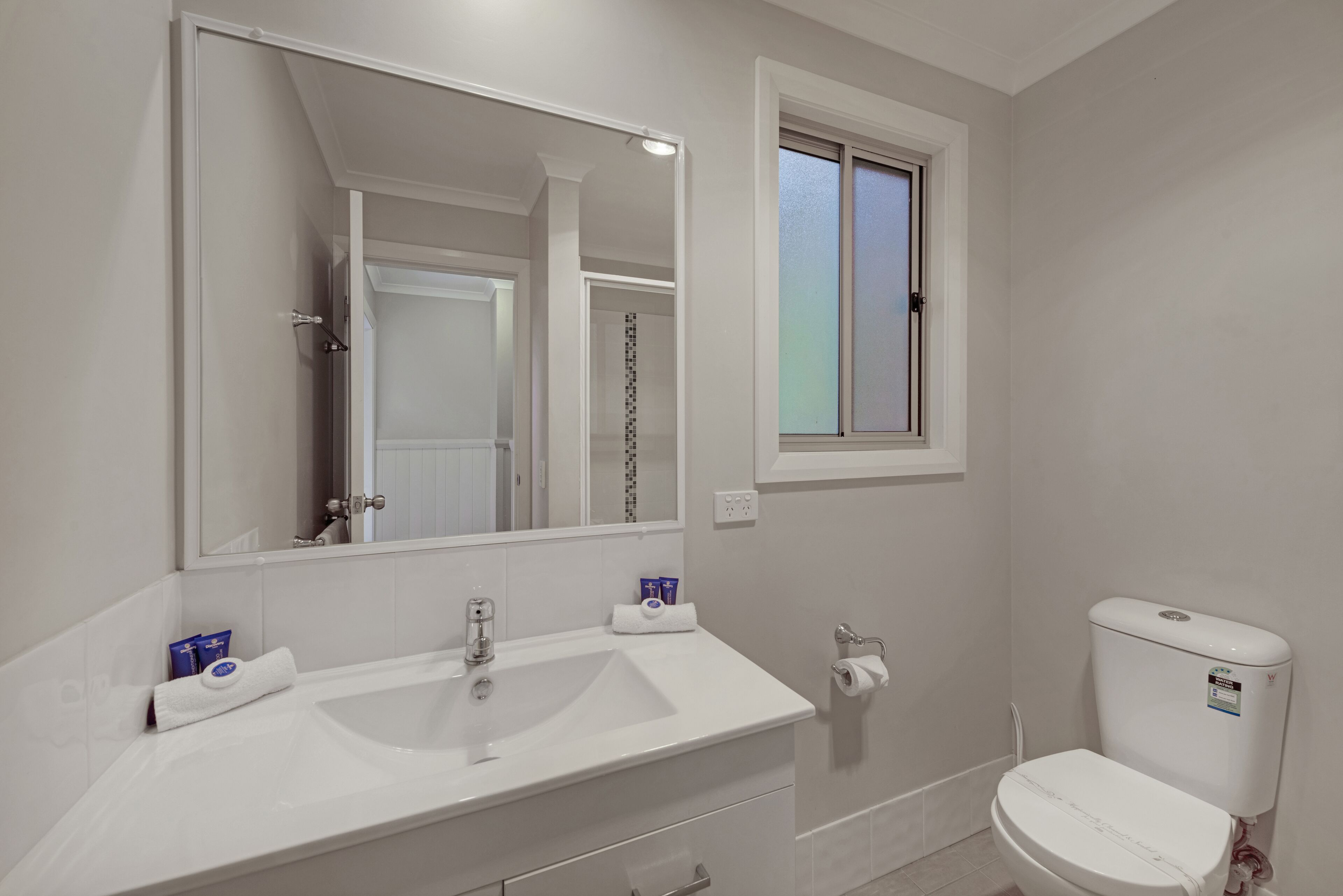 A bathroom with a white sink, mirror, and toilet.