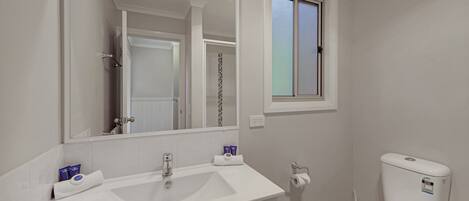 A bathroom with a white sink, mirror, and toilet.