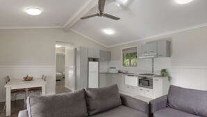 Una cocina moderna con muebles blancos, un comedor con mesa y sillas blancas, y un sofá gris en la sala.