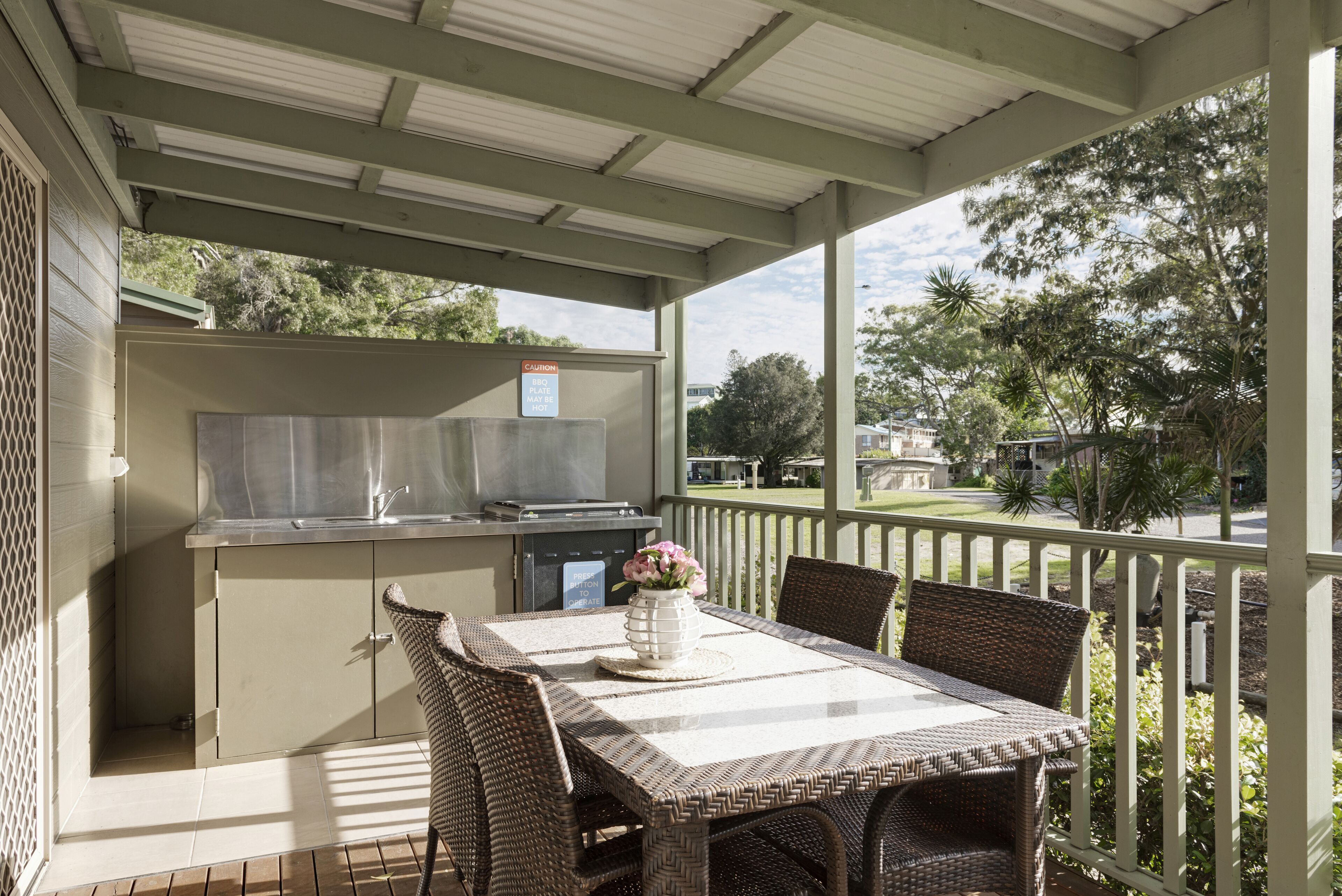 An outdoor patio with a grill, dining table, and chairs.