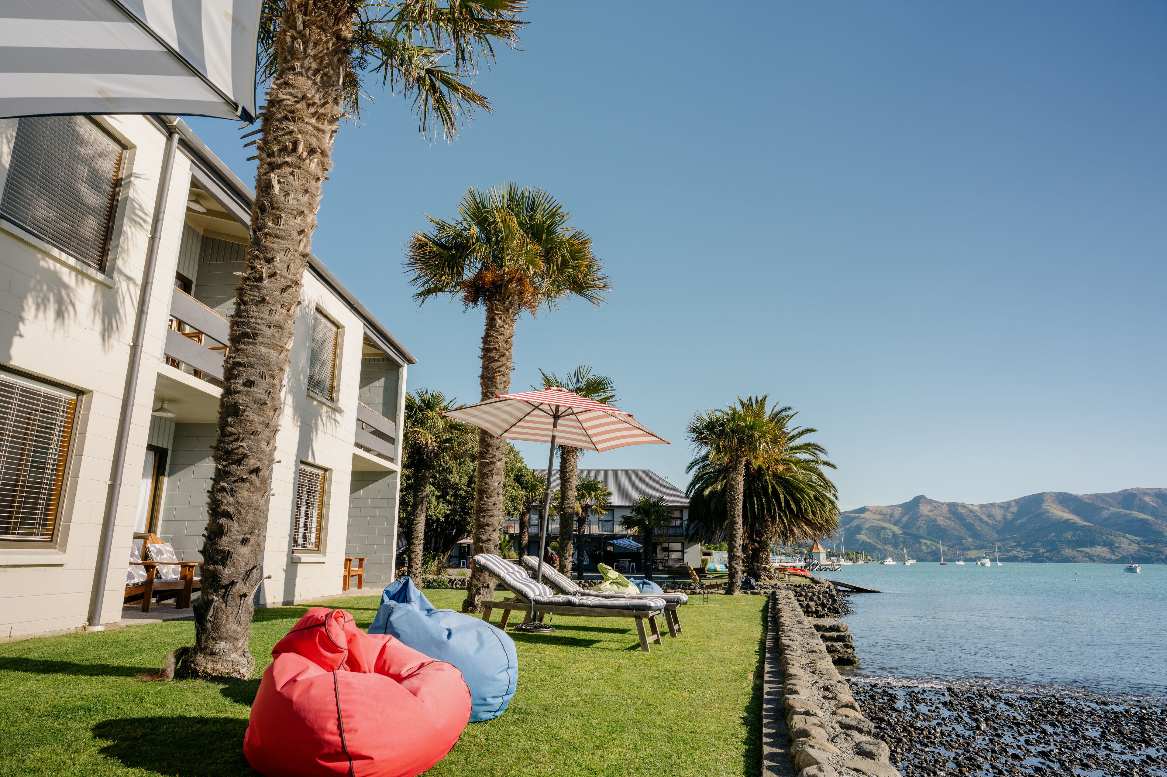 Ett hotell vid stranden med solstolar, palmer och utsikt över havet.