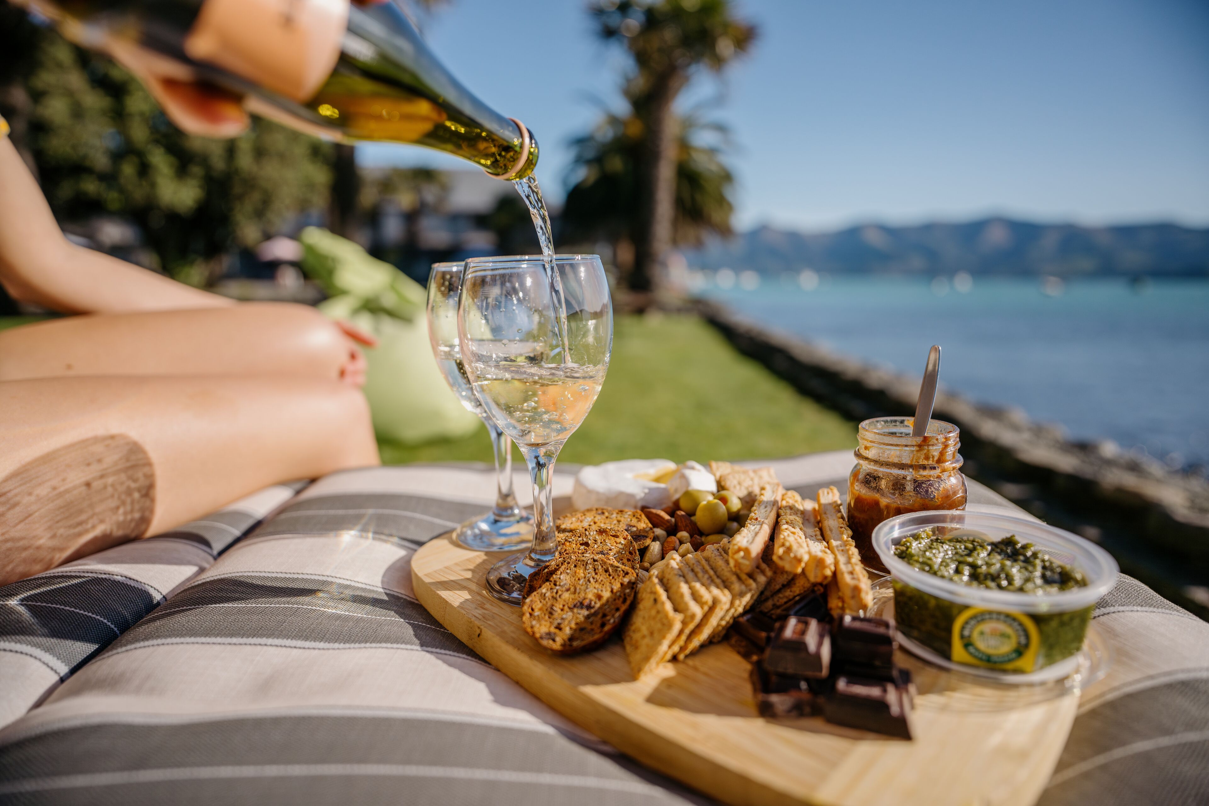 A table with a bottle of water, a glass, and a board with snacks and a jar of spread.