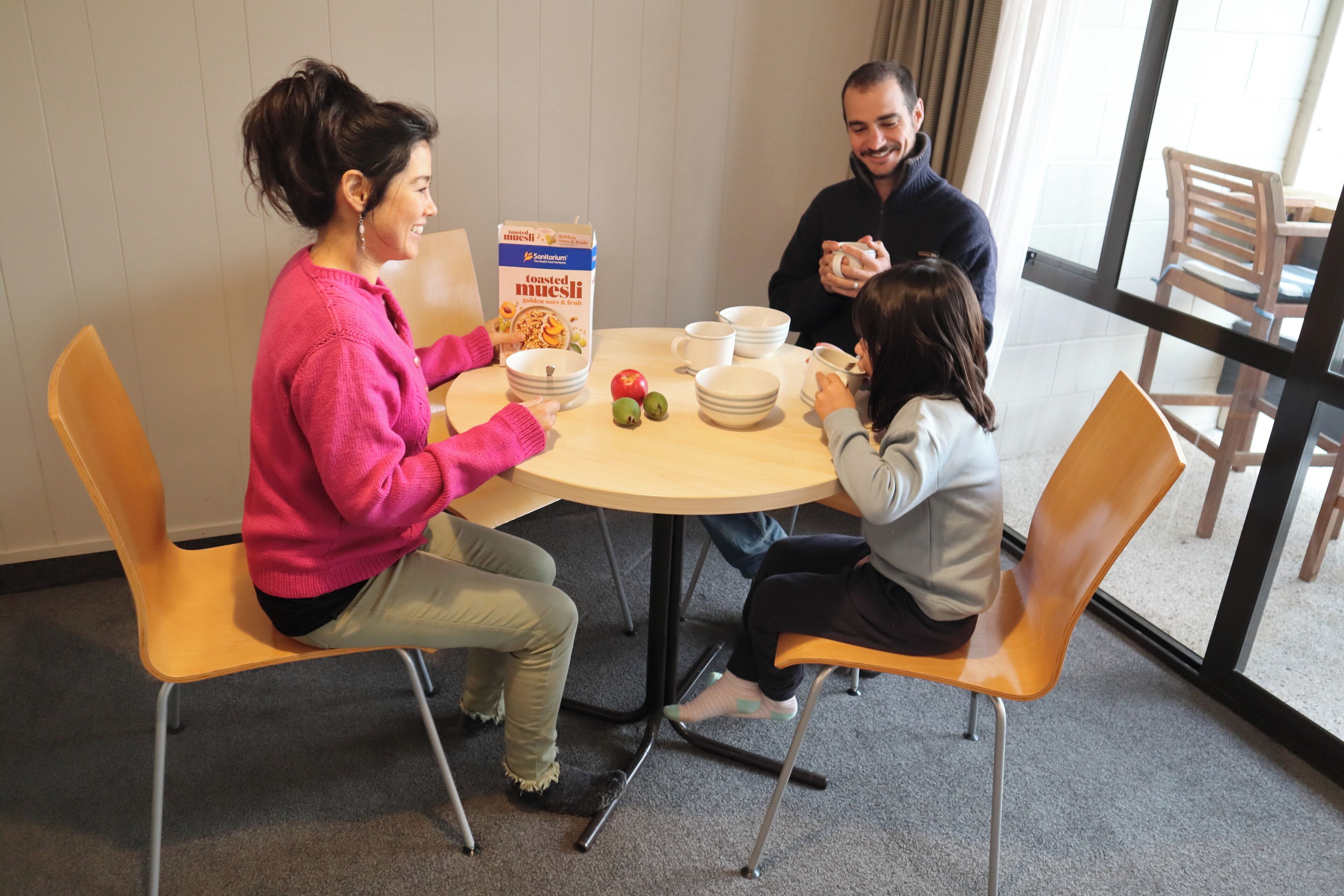 Un coin repas avec une table ronde, des chaises et une boîte de muesli grillé.