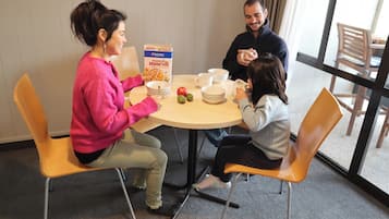 A dining area with a round table, chairs, and a box of toasted muesli.