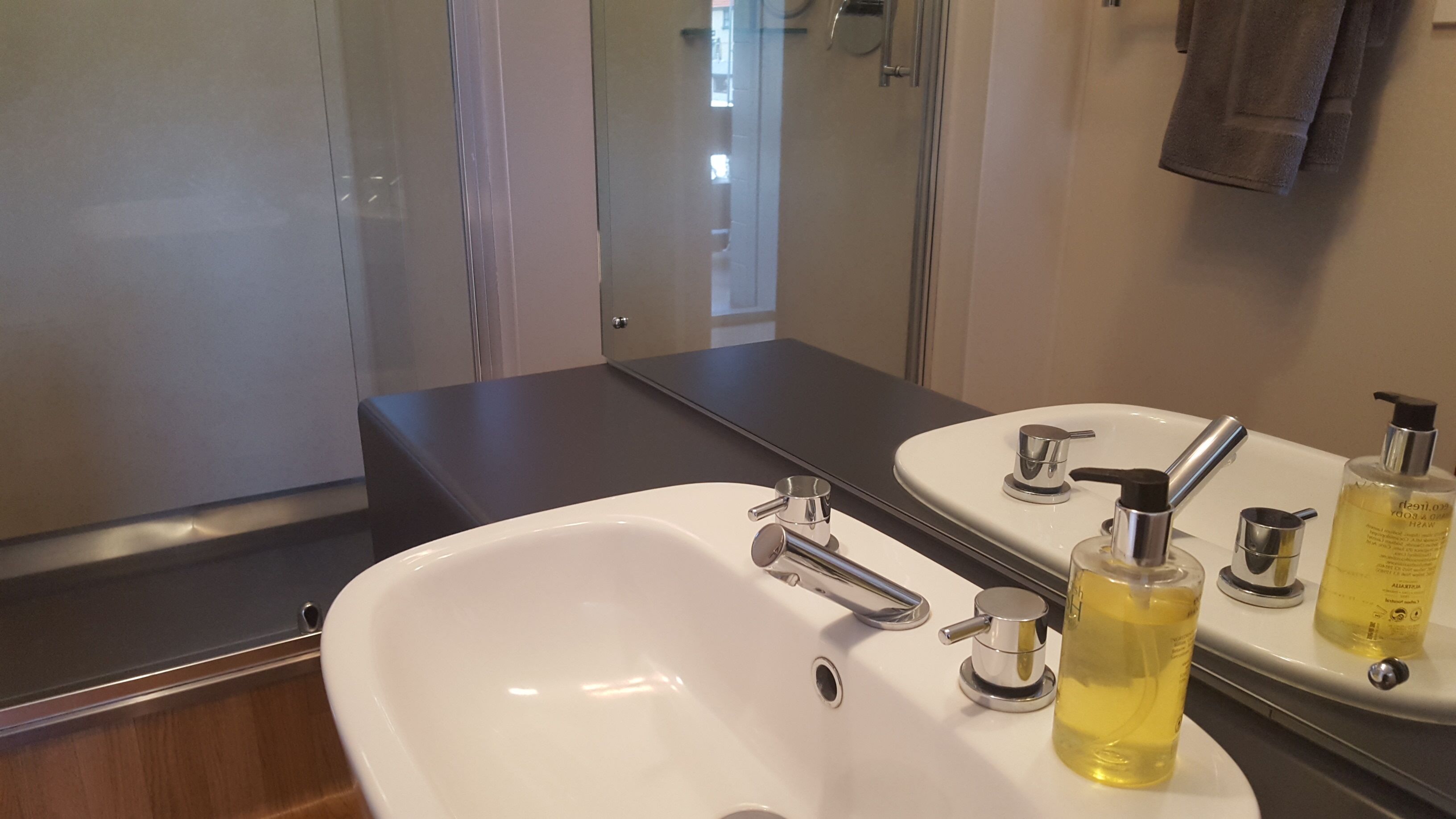Ett badrum med ett vitt handfat, en spegel och två flaskor med lotion.