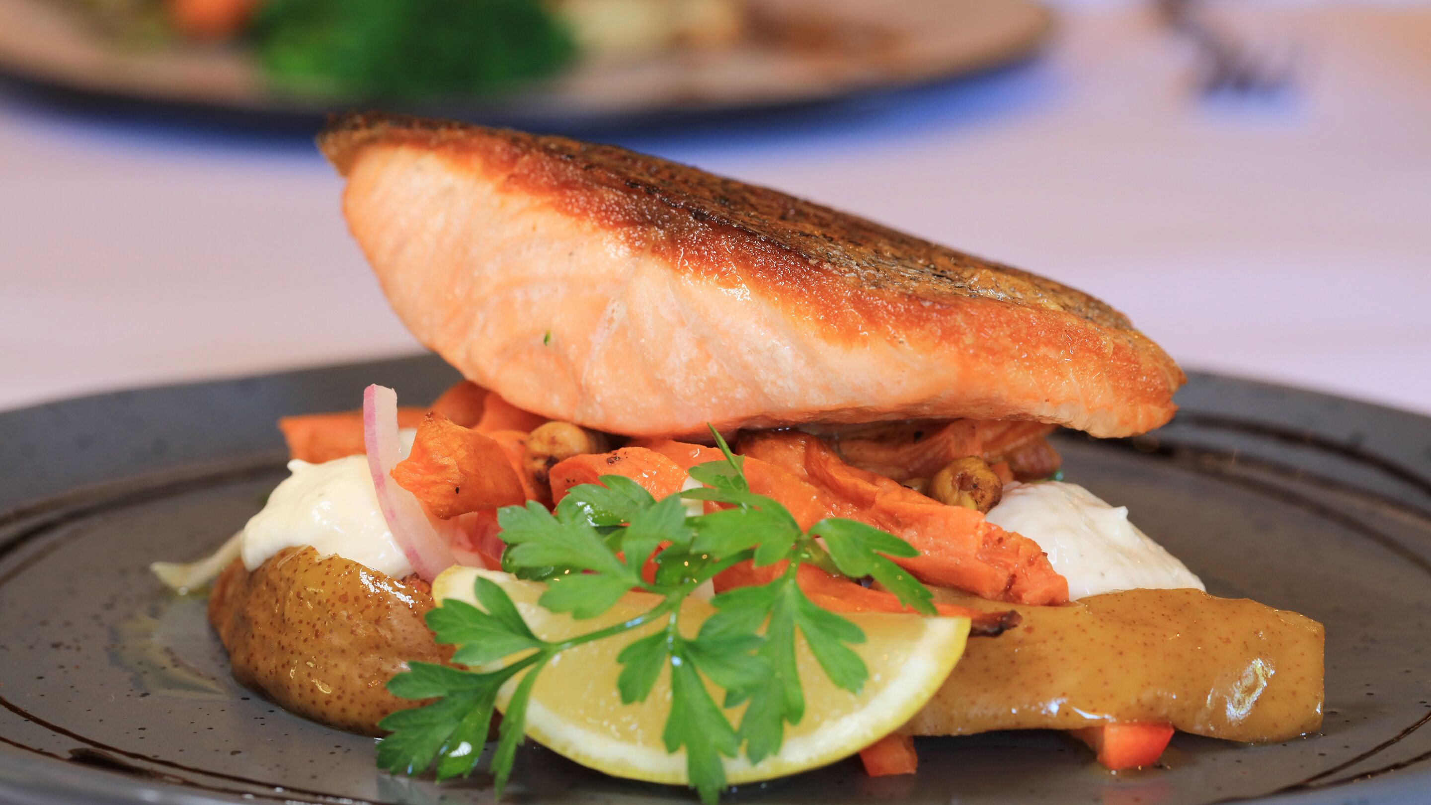 Une assiette contenant un morceau de saumon, une pomme de terre et quelques légumes.