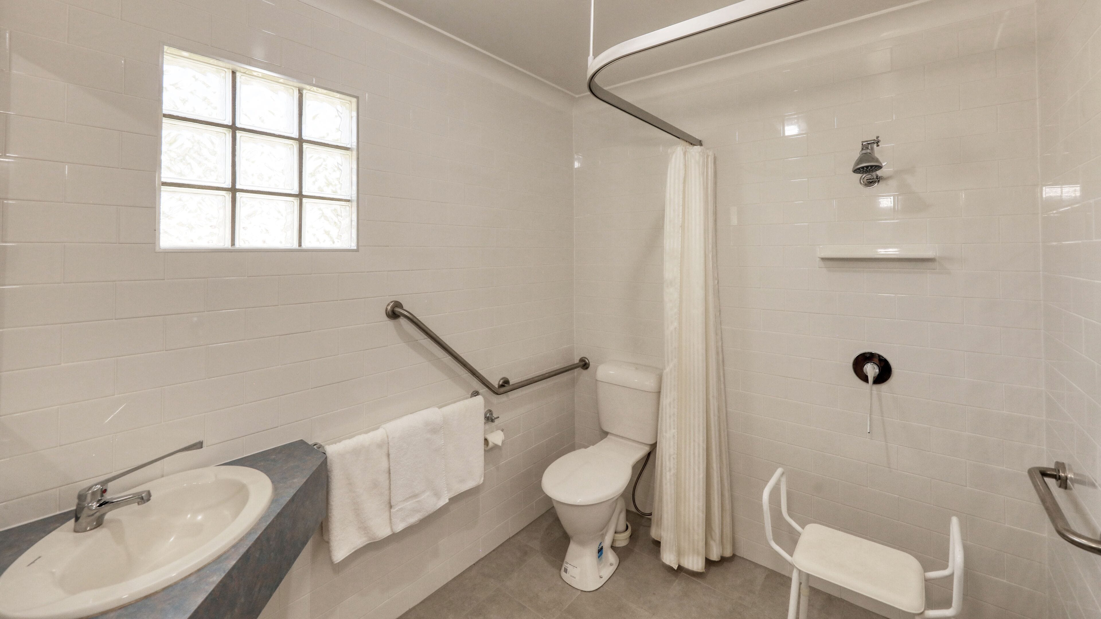 Un baño con lavamanos, inodoro, ducha y ventana.