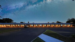 A motel with a row of rooms, a parking lot, and a clear night sky with stars.