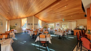 Un vaste espace dédié à la salle à manger, avec de nombreuses tables et chaises, un plafond en bois et des murs en briques.