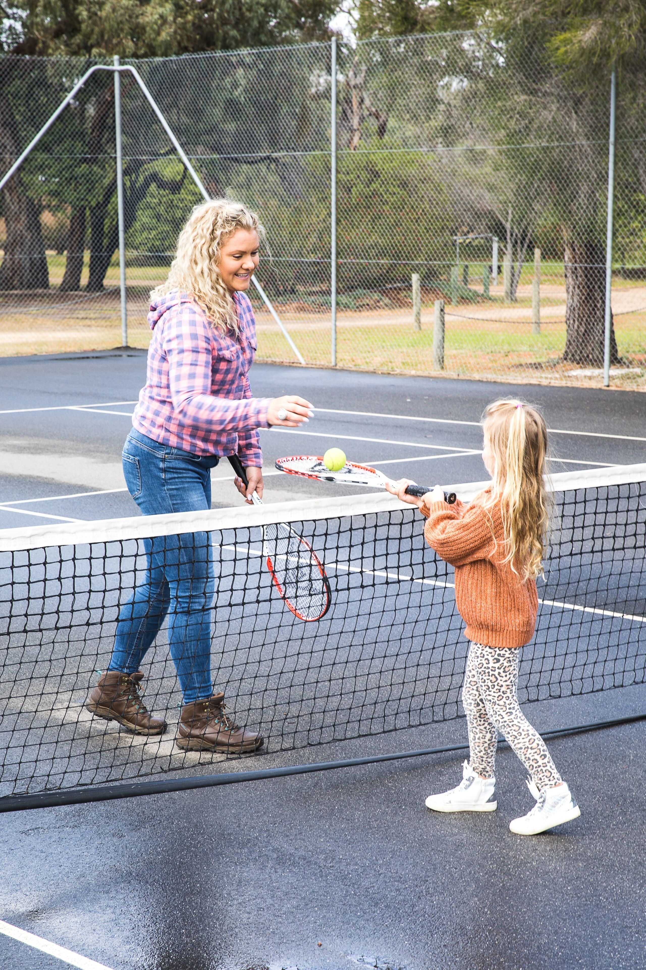 Een tennisbaan met een net in het midden, een tennisbal en twee spelers.