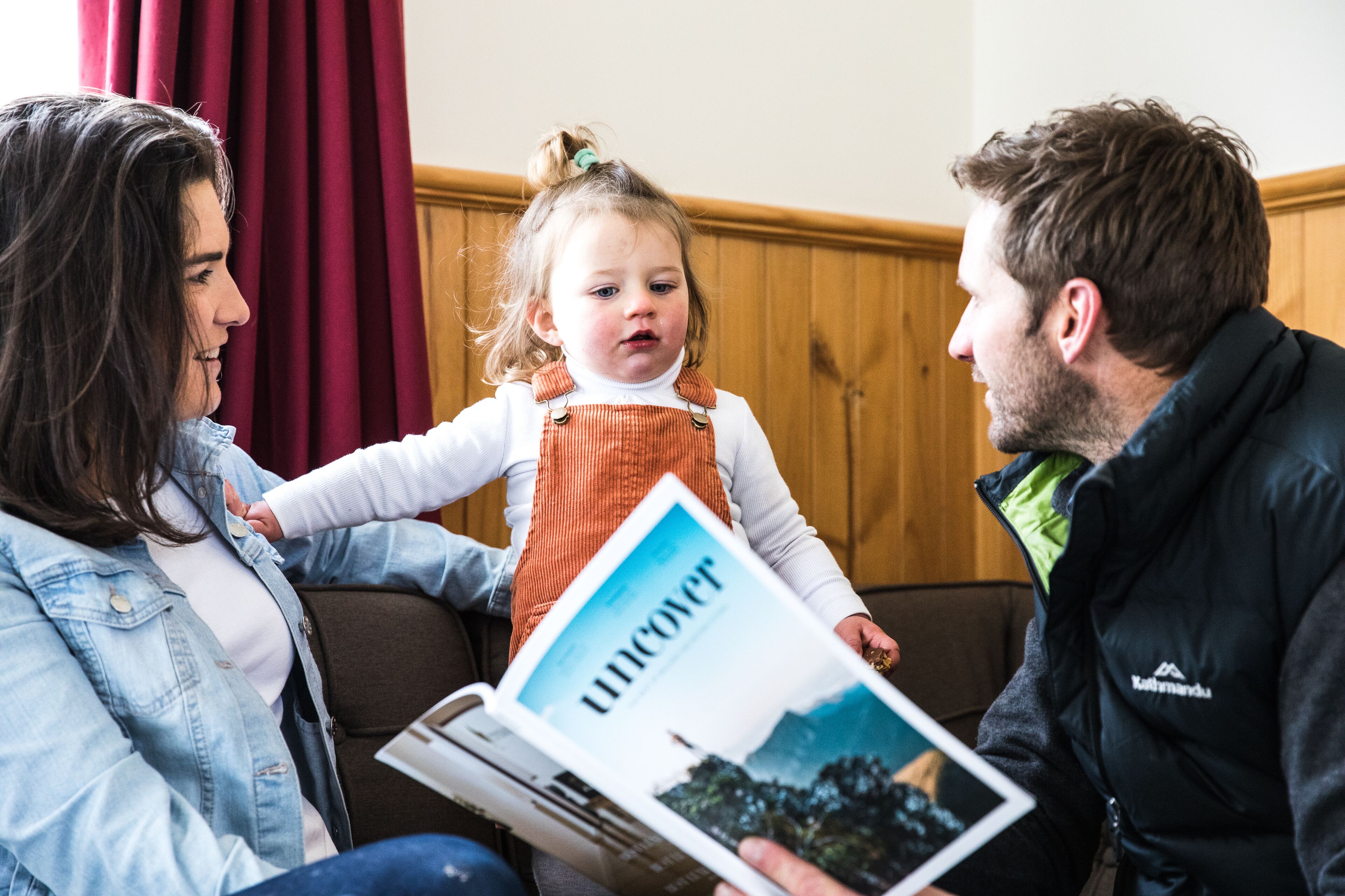 A family sitting on a couch with a magazine.
