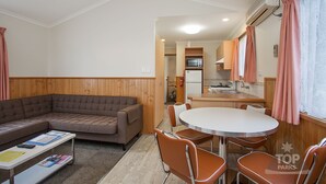 Un espacio habitable compacto con sofá, una mesa de comedor con sillas, una kitchenette y una pequeña zona de cocina.
