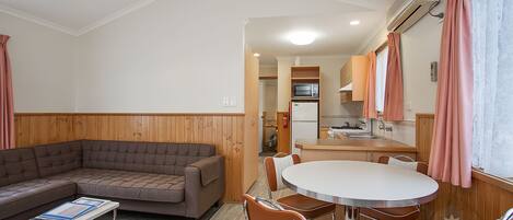 A compact living space with a sofa, a dining table with chairs, a kitchenette, and a small kitchen area.