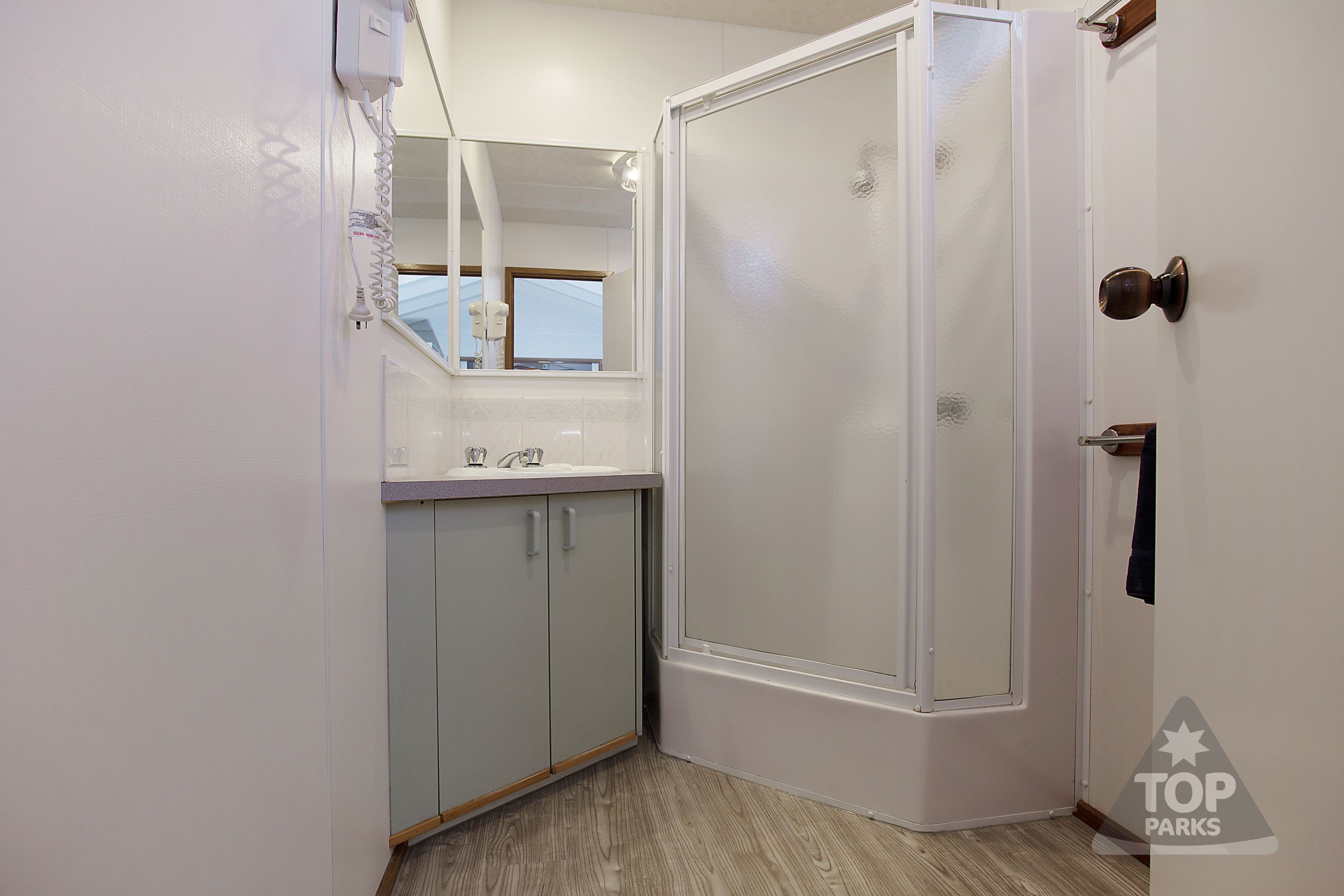 A bathroom with a shower, a sink, and cabinets.