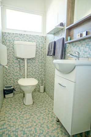 A bathroom with a toilet, sink, and a window above the toilet. - Meningie's Waterfront Motel (Meningie)