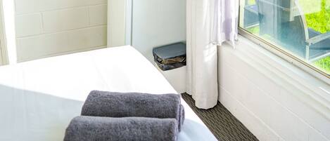 A hotel room with a bed, a desk, a flat-screen TV mounted on the wall, and a window with a view of the outdoors.