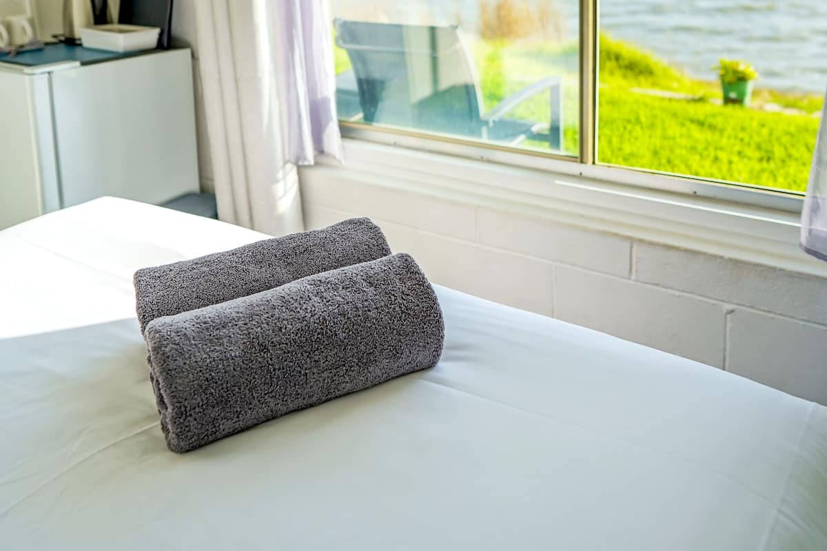 Habitación de hotel con cama, escritorio con computadora y vista al mar.