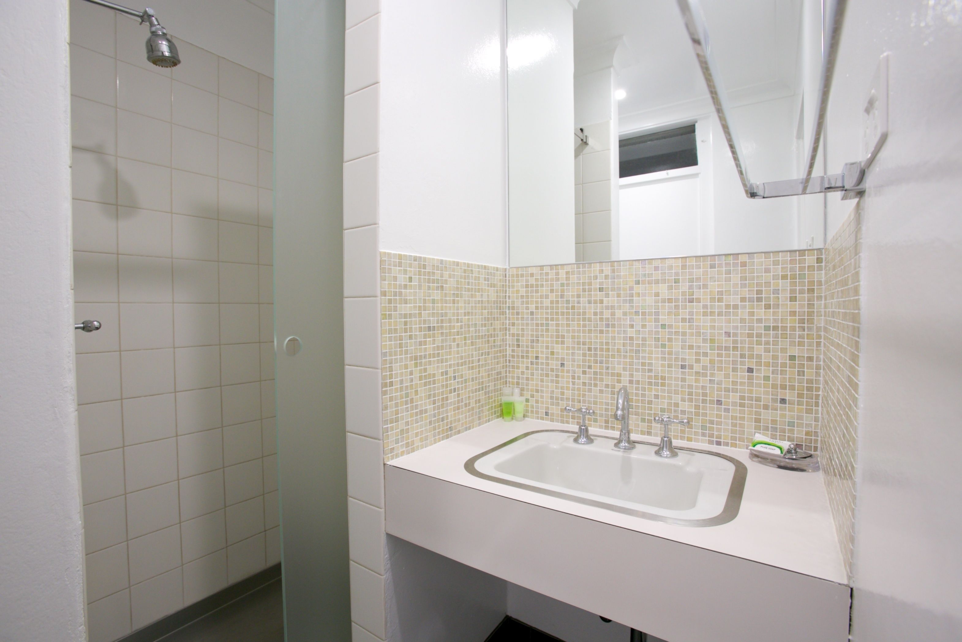 Un bagno con doccia, lavandino e specchio.