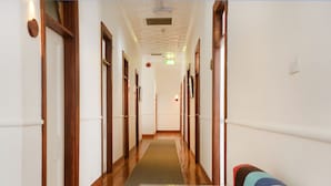 Un pasillo de hotel con puertas de madera, alfombra verde y un sofá colorido.