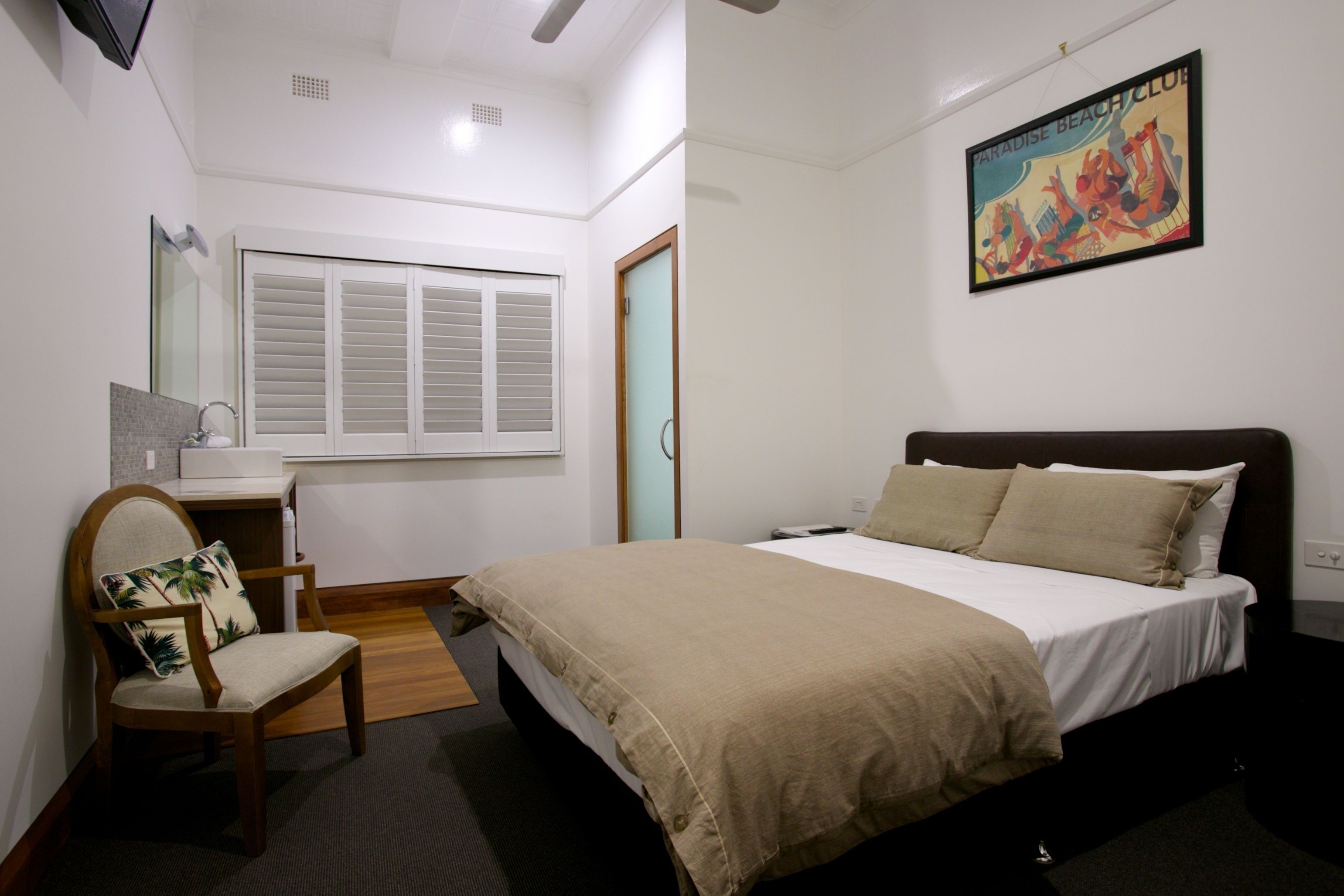 A bedroom with a bed, a chair, a desk, and a window.