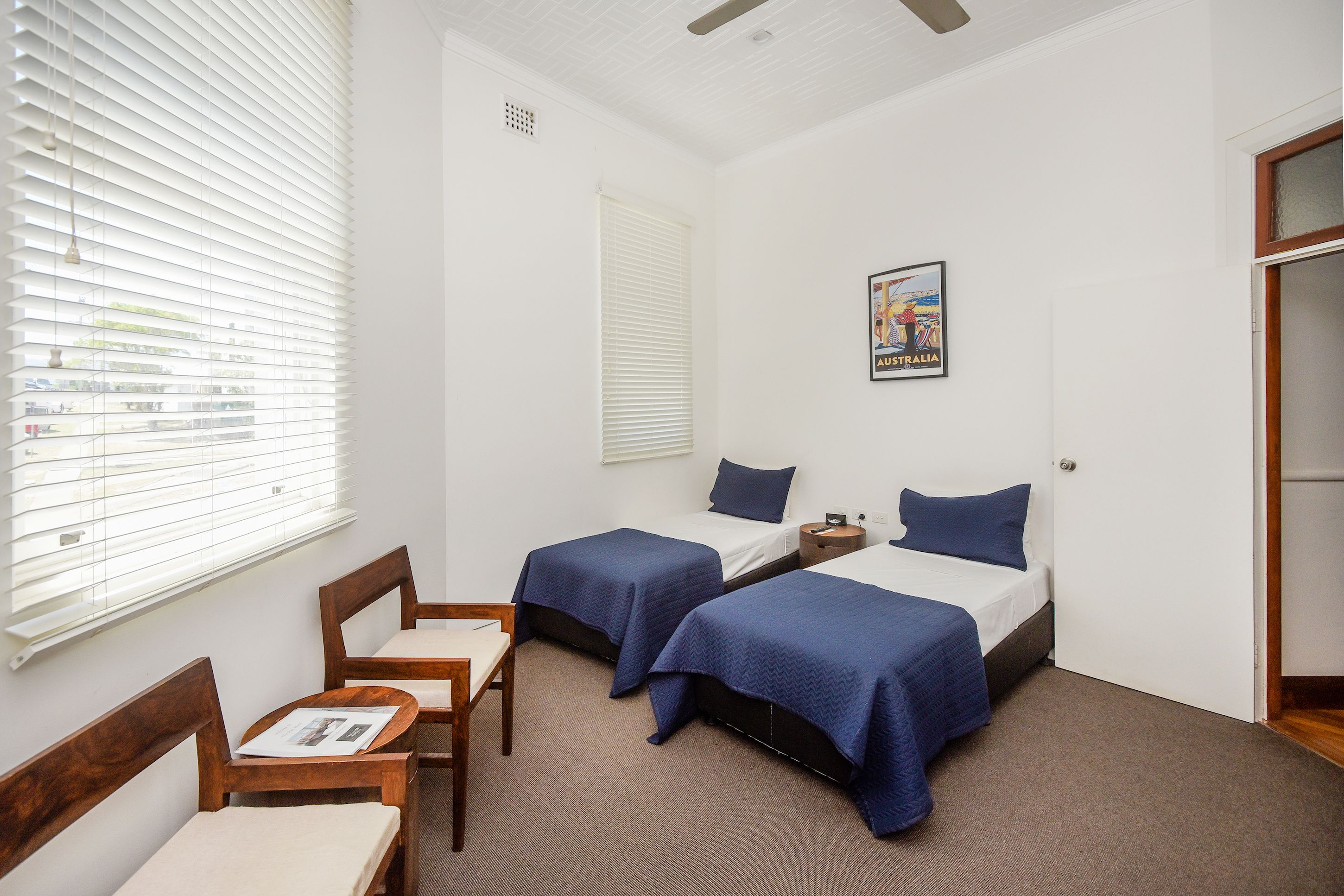 A hotel room with two beds, a small table, and a chair.