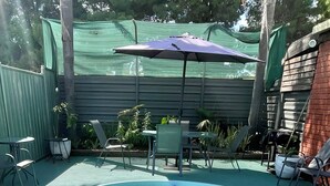 A clear swimming pool with a white edge, surrounded by a green fence and a wooden deck. - Country Roads Motor Inn Narrandera (Narrandera)
