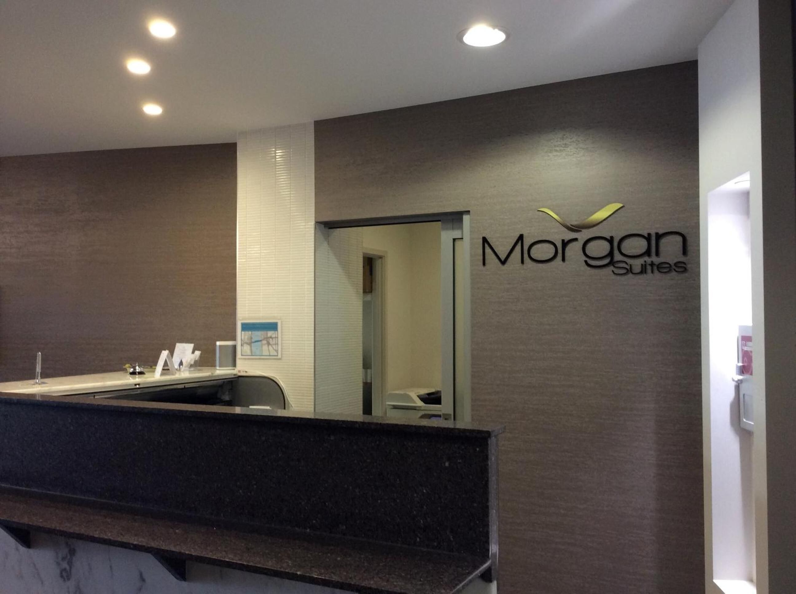 Zona de recepción con mostrador, espejo y cartel de Morgan Suites.