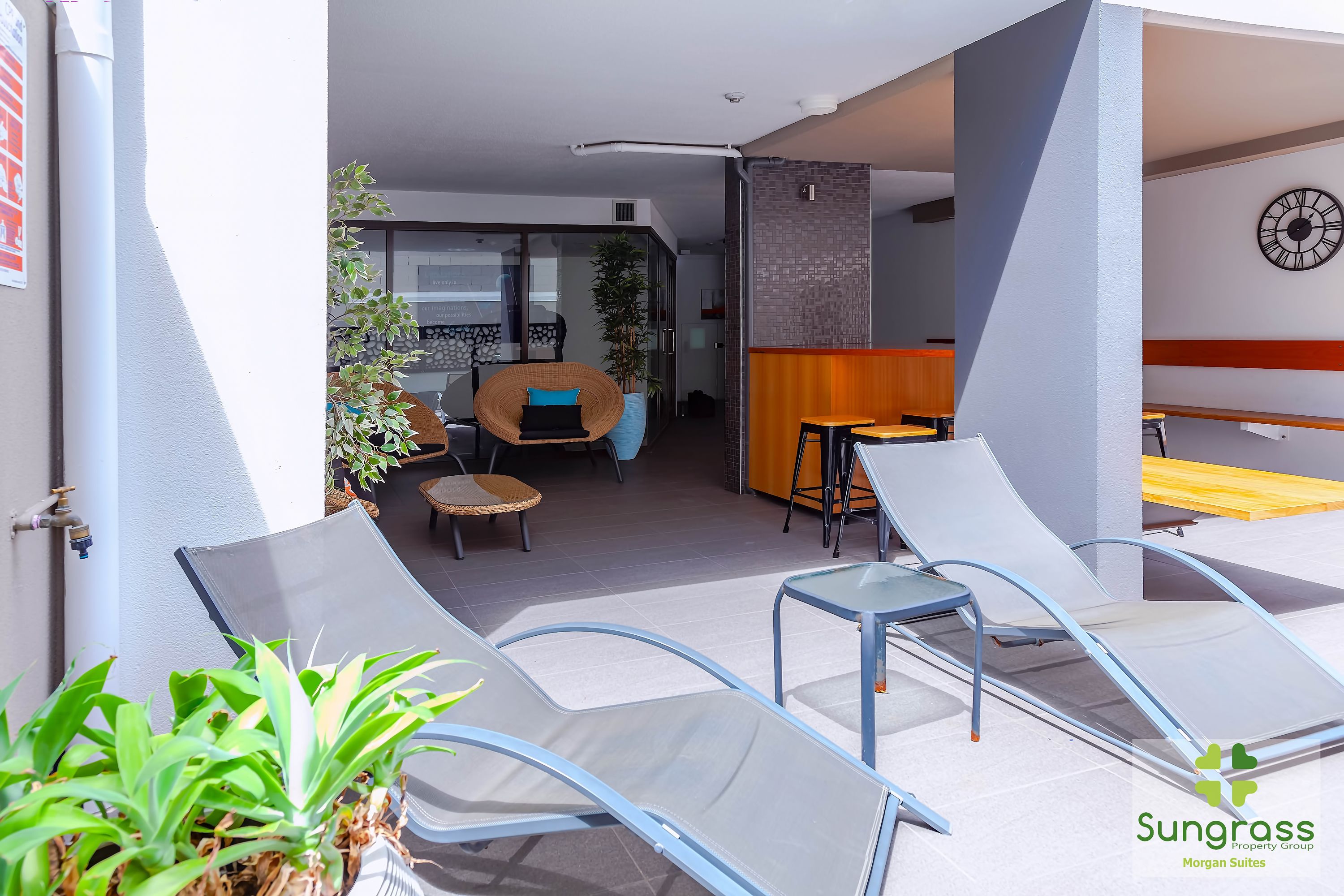 Un espace de détente extérieur moderne, comprenant des fauteuils, une petite table et un coin salon avec une chaise et une plante.