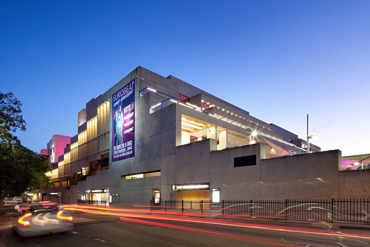Un bâtiment moderne sur lequel est installé un grand panneau publicitaire annonçant un événement.