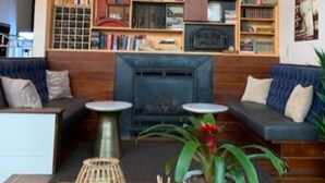 A cozy interior with a fireplace, wooden bookshelves, and comfortable seating. - Commodore Hotel (Astoria)