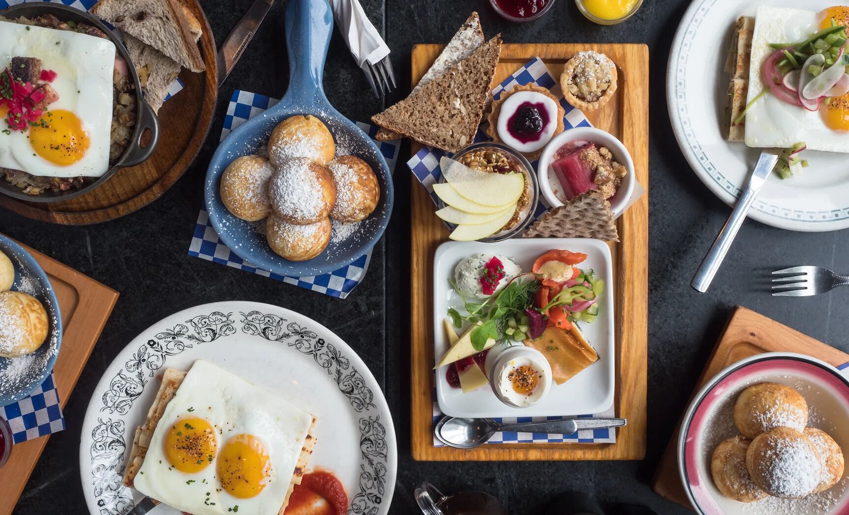 A breakfast setting with various dishes including eggs, pastries, and a salad.