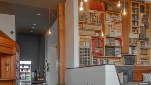 A modern interior with wooden floors, a seating area, and a wall with various items and a clock. - Commodore Hotel (Astoria)