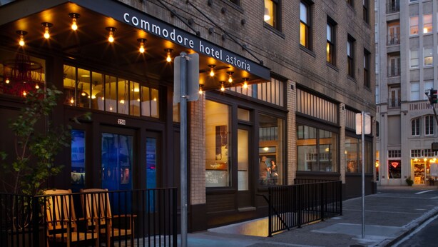A brick building with a storefront labeled "commodore hotel." - Commodore Hotel (Astoria)