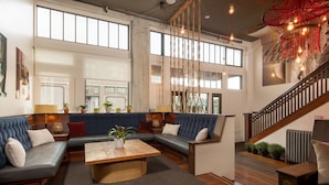 A spacious living area with a large sectional sofa, a coffee table, and a staircase with a wooden railing. - Commodore Hotel (Astoria)