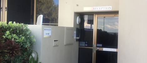 A reception area with a glass door, a sign indicating 'Reception', and a 'Manager' sign pointing to the left.