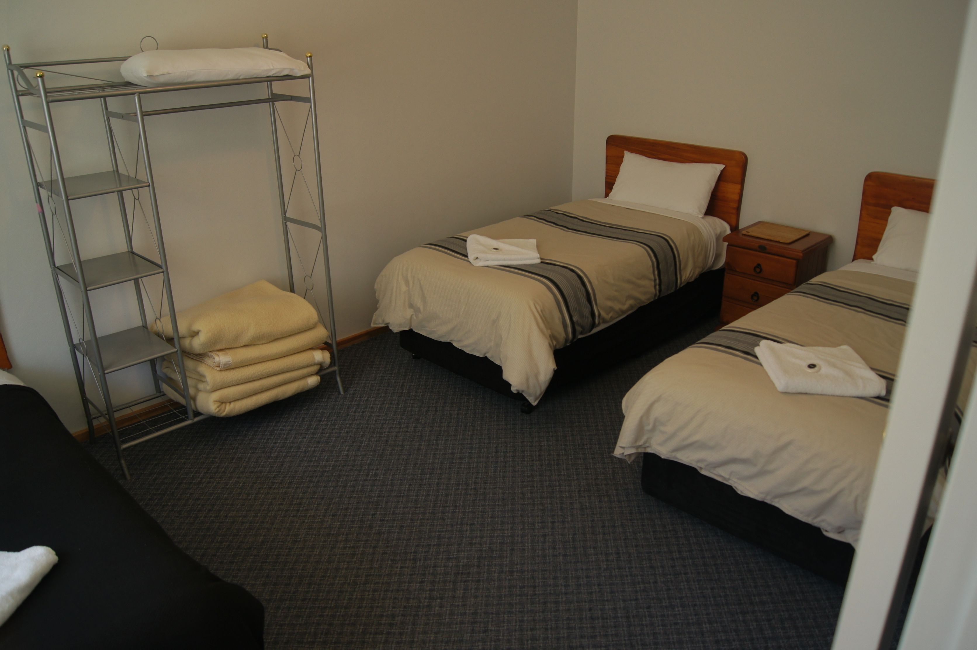 A hotel room with two single beds, a bunk bed, and a small wooden nightstand.