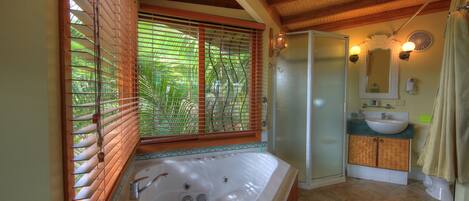 A bathroom with a large bathtub, a shower, and a sink.